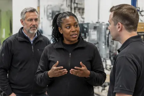 A senior manager leading an office discussion as a colleague listens nearby